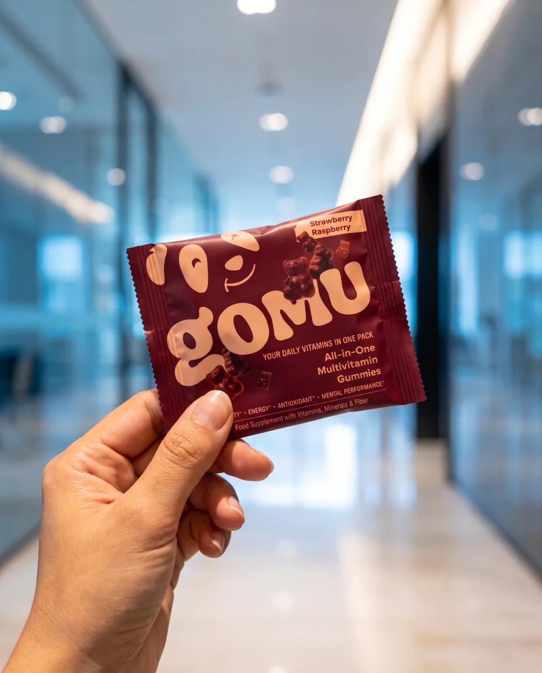 A hand holding a GOMU daily sachet in an air-conditioned interior